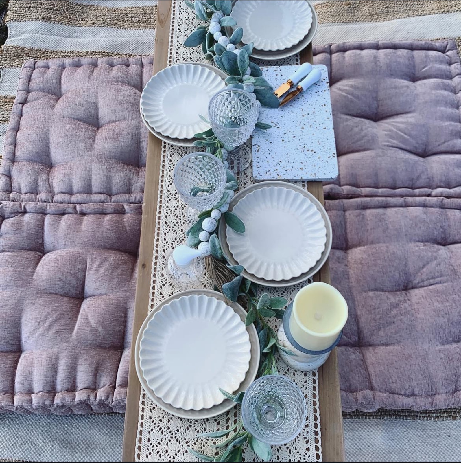 Overhead four-place setting with lace runner, fluted plates, and lamb’s ear.